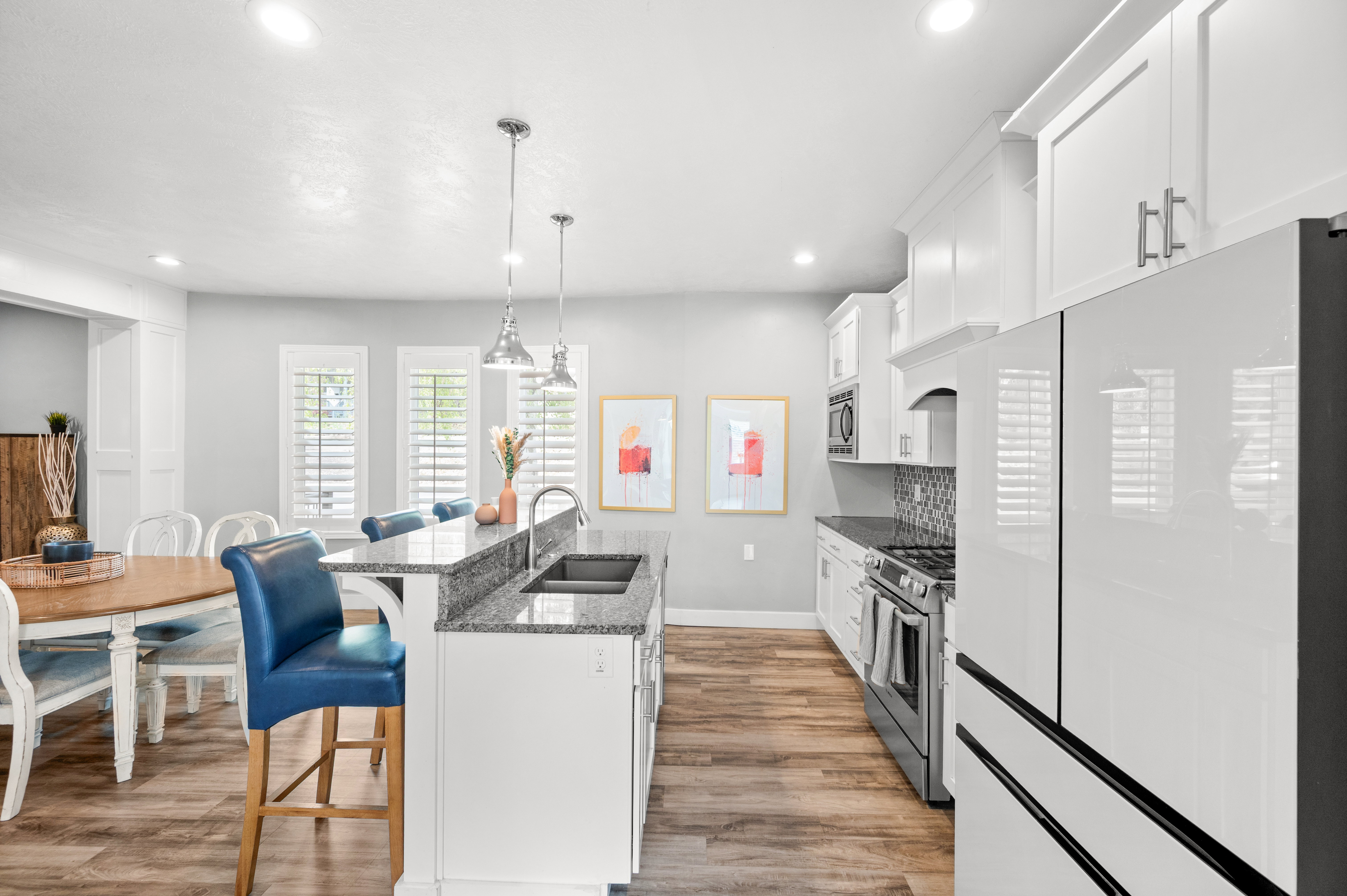 Kitchen featuring a breakfast bar area, stainless steel appliances, an island with sink, white cabinets, and dark stone countertops
