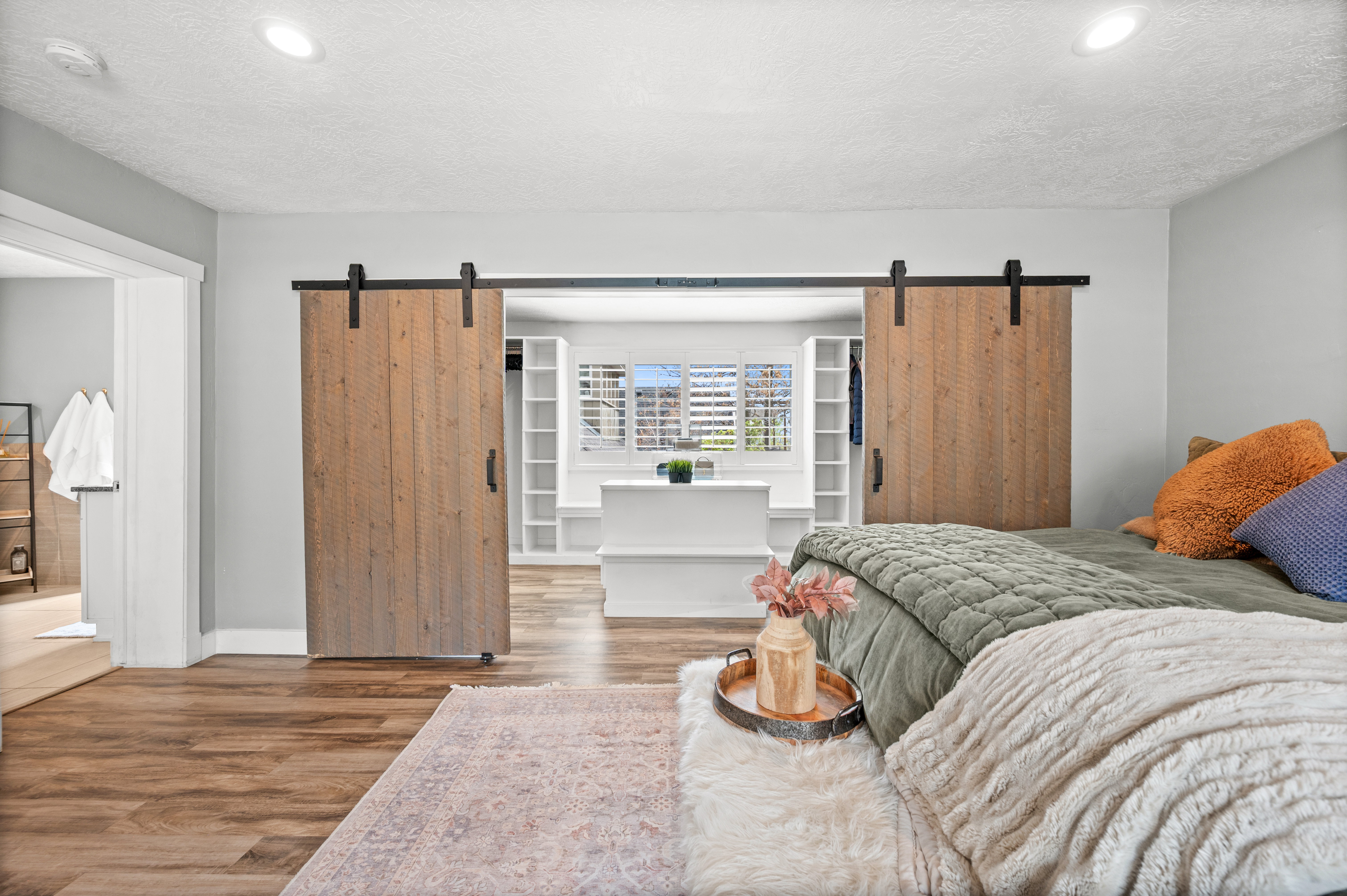 Bedroom with a barn door, wood finished floors, and a textured ceiling