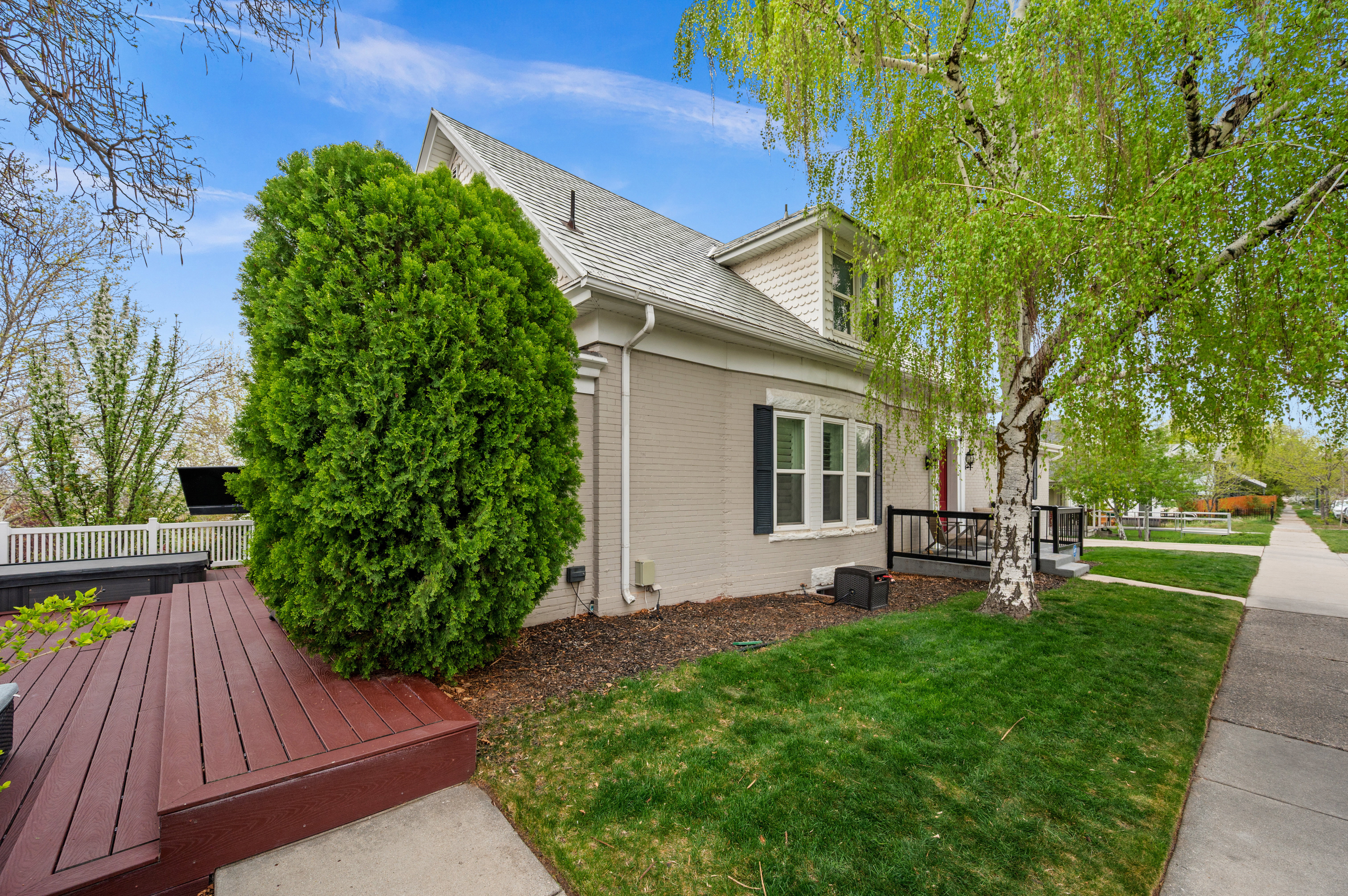 View of side of home with a deck, a yard, brick siding, and roof with shingles