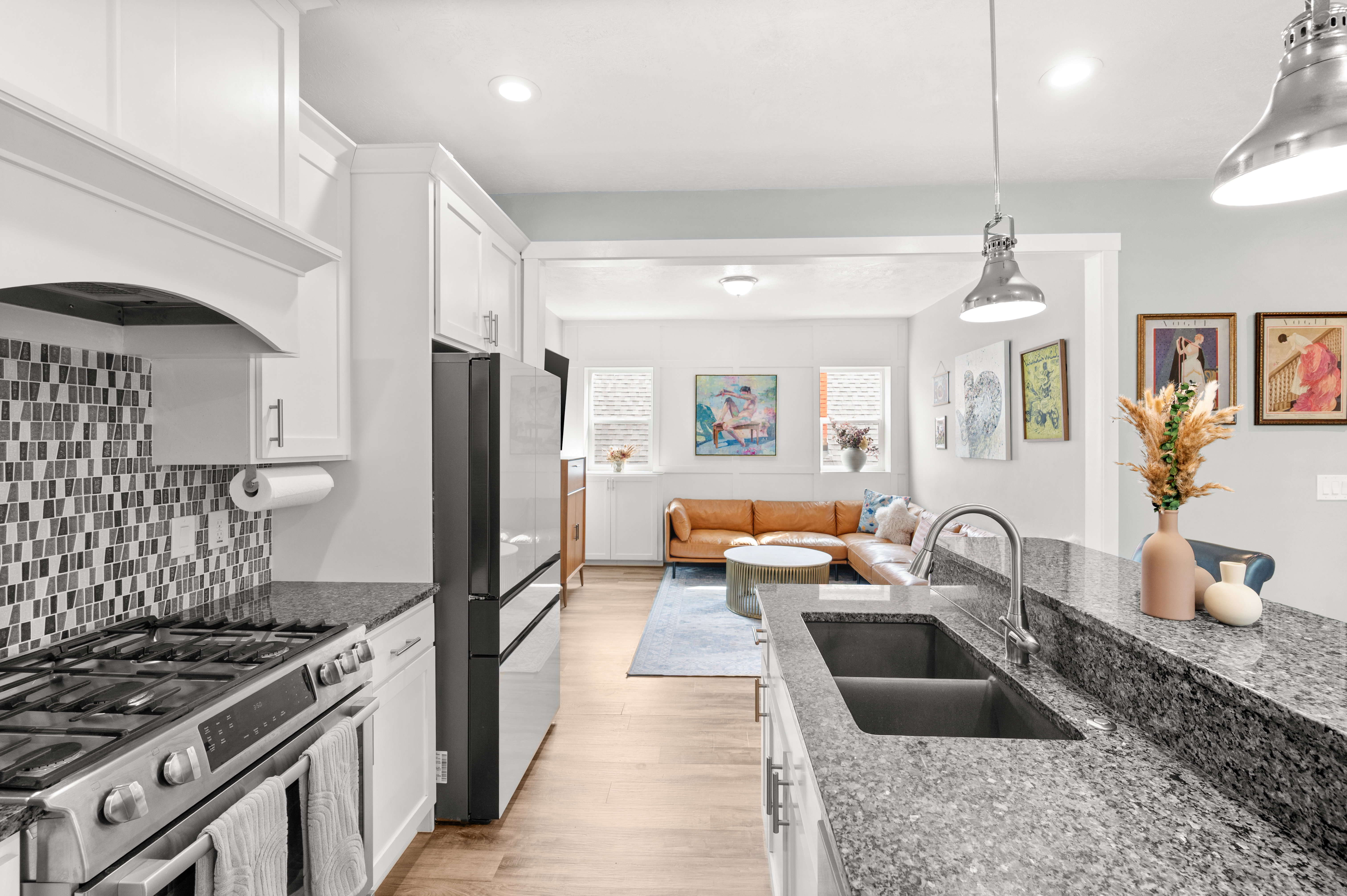 Kitchen with white cabinets, stainless steel gas range oven, dark stone countertops, and open floor plan