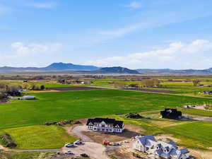 Aerial view of back of home featuring mountains and agricultural land