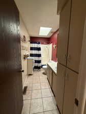 Full bath with vanity, a skylight, light tile patterned flooring, and shower / bath combination with curtain