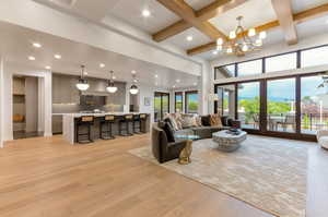 Living area featuring light wood-style flooring, coffered ceiling, and suspended lighting