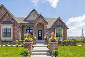 View of front facade with a front lawn, stucco siding, a shingled roof, and brick siding