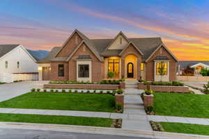 Tudor house with brick siding, roof with shingles, driveway, and a garage