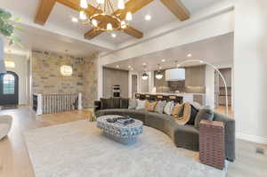 Living room featuring suspended lighting, light wood-style floors, and coffered ceiling