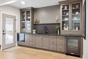 Bar with glass fronted cabinets, gray cabinetry, wine cooler, stainless steel microwave, and recessed lighting