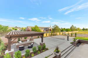 View of tennis court featuring a patio, a residential view, and basketball hoop