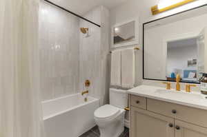 Full bath with shower / bath combination with curtain, vanity, ensuite bathroom, and dark tile patterned floors