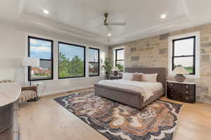 Bedroom featuring light wood-style floors, a ceiling fan, a raised ceiling, and recessed lighting