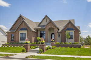 Tudor house featuring brick siding, a front yard, a shingled roof, and stucco siding
