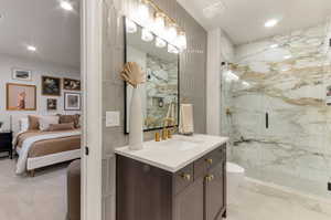 Ensuite bathroom with recessed lighting, vanity, and a marble finish shower