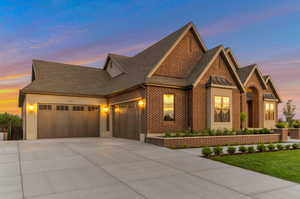 View of front of property with brick siding, roof with shingles, a garage, and concrete driveway