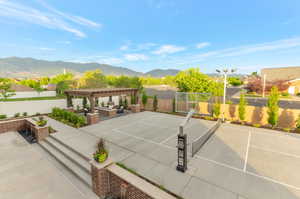 View of tennis court with a fenced backyard, a pergola, a patio area, a mountain view, and outdoor seating