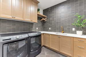 Laundry room featuring washer and clothes dryer, cabinet space, and light tile patterned flooring