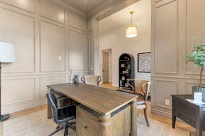 Office area featuring a decorative wall, light wood-style flooring, and a high ceiling