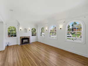 Unfurnished living room featuring a tiled fireplace and wood finished floors