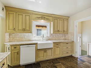 Kitchen with dishwasher, backsplash, arched walkways, and light stone counters