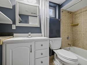 Full bathroom with vanity, shower / bath combo with shower curtain, and a textured ceiling