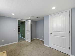 Below grade area with light colored carpet, recessed lighting, and a textured ceiling