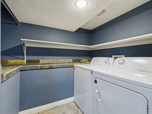 Laundry room featuring separate washer and dryer and a textured ceiling