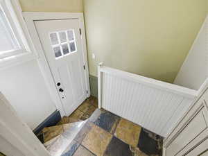 Entryway with stone tile floors and a wainscoted wall