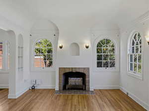 Unfurnished living room with a fireplace with flush hearth, lofted ceiling, and light wood-style floors