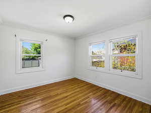 Empty room with hardwood / wood-style floors and ornamental molding