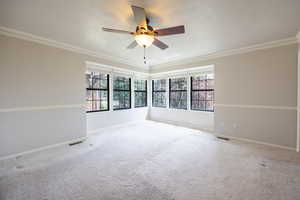 Primary bedroom with corner window set, crown moulding and ceiling fan.