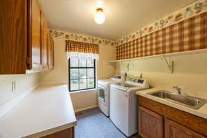 Large laundry room with folding table, sink, and cabinets for storage.