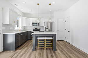 Two tone kitchen with two tone cabinetry, stainless steel appliances, a center island, a breakfast bar area, and light wood-style flooring