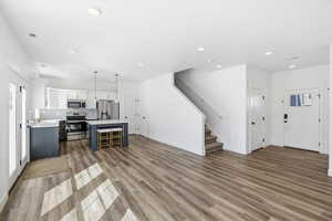 Dual tone kitchen with two tone color scheme, open floor plan, stainless steel appliances, a kitchen island, and light wood-type flooring