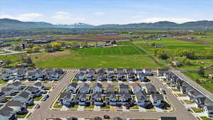 Aerial view of property and surrounding area featuring a mountainous background and nearby suburban area
