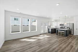 Kitchen with light countertops, dual tone cabinetry, stainless steel appliances, a center island, and open floor plan