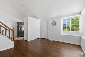 Foyer with dark wood-style floors and lofted ceiling