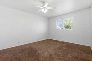Spare room with dark carpet and ceiling fan