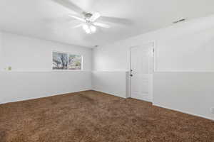 Unfurnished room featuring dark carpet and a ceiling fan