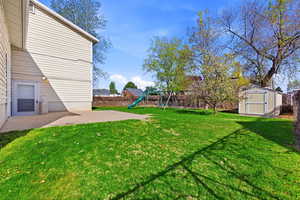Fenced yard featuring a patio, a storage shed, and a playground