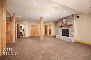 Unfurnished living room with carpet flooring, a stone fireplace, and recessed lighting