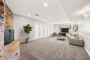 Living room featuring carpet, a brick fireplace, and recessed lighting