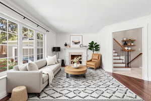 Living area with wood finished floors, a fireplace, and crown molding