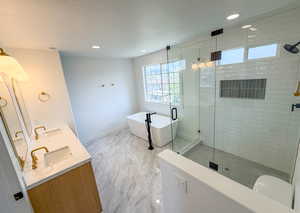 Bathroom featuring a freestanding bath, double vanity, a stall shower, and recessed lighting