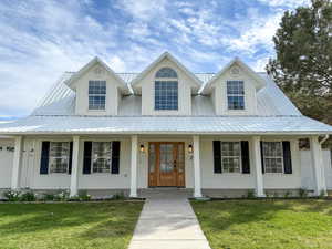 View of front of property featuring covered porch, a front lawn, and a metal roof