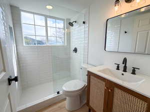 Full bathroom featuring vanity, a stall shower, and light wood finished floors