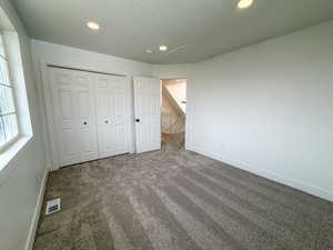Unfurnished bedroom featuring dark colored carpet, a closet, and recessed lighting