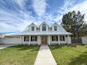 View of front facade featuring covered porch, a front lawn, a metal roof, and concrete driveway