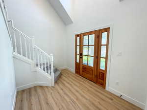 Foyer entrance with light wood-style flooring and a high ceiling