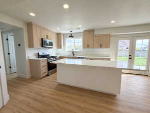 Kitchen featuring stainless steel appliances, a kitchen island, french doors, light stone countertops, and recessed lighting