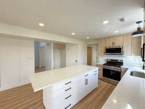 Kitchen with a center island, light stone counters, and stainless steel appliances