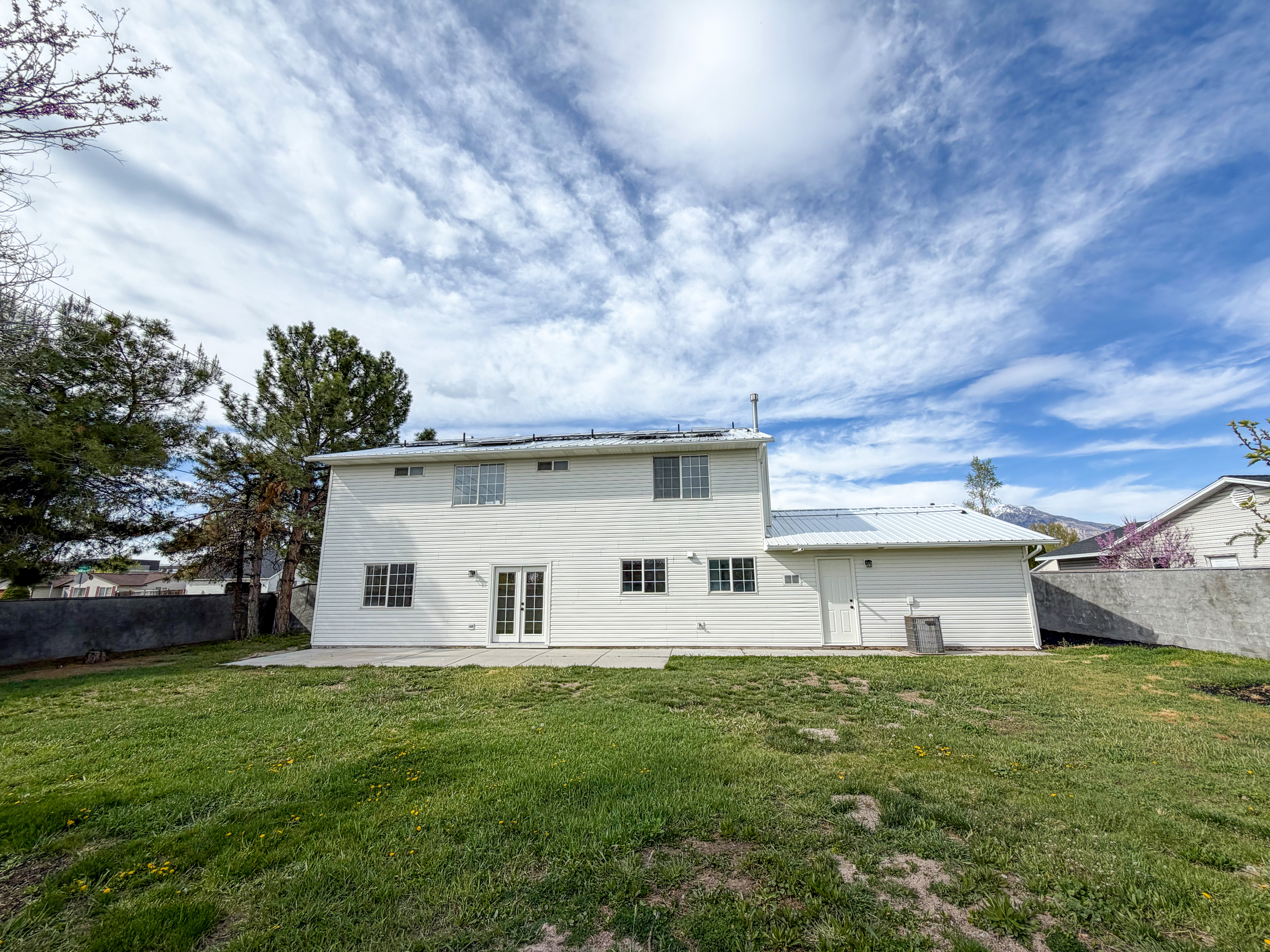 Back of house featuring french doors, a patio, a metal roof, and roof mounted solar panels